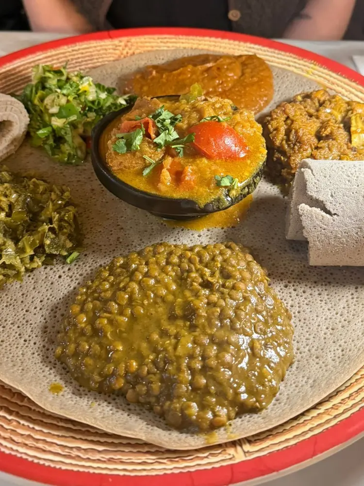 Vegan combo platter on injera with lentils, greens and salad